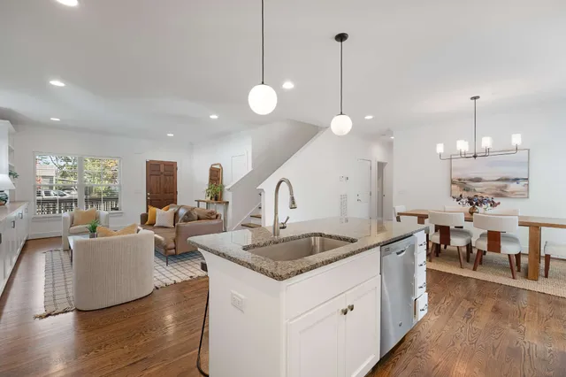 a open kitchen with stainless steel appliances granite countertop a stove a sink a kitchen island with couches table and chairs