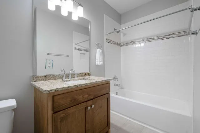 a bathroom with a granite countertop sink a toilet and shower