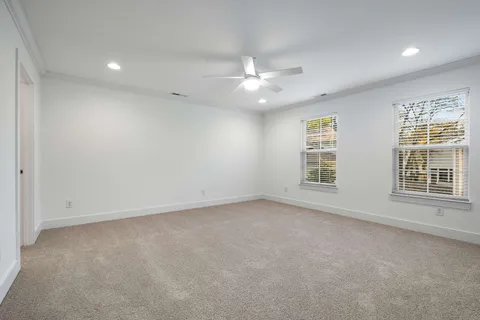 an empty room with a ceiling fan and windows