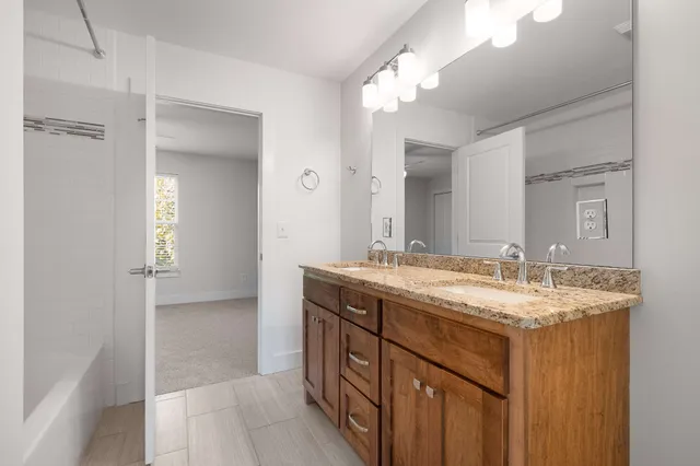 a bathroom with a granite countertop double vanity sink and a mirror