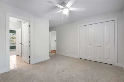 an empty room with closet and a ceiling fan