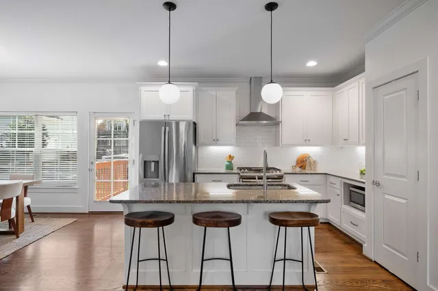 a kitchen with stainless steel appliances kitchen island granite countertop a stove a chimney a sink and cabinets