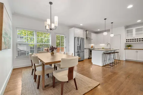 a view of a dining room and livingroom with furniture wooden floor a chandelier