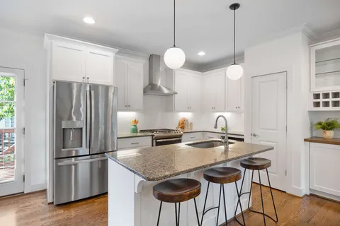 a kitchen with stainless steel appliances granite countertop a sink a stove a refrigerator and island with wooden floor