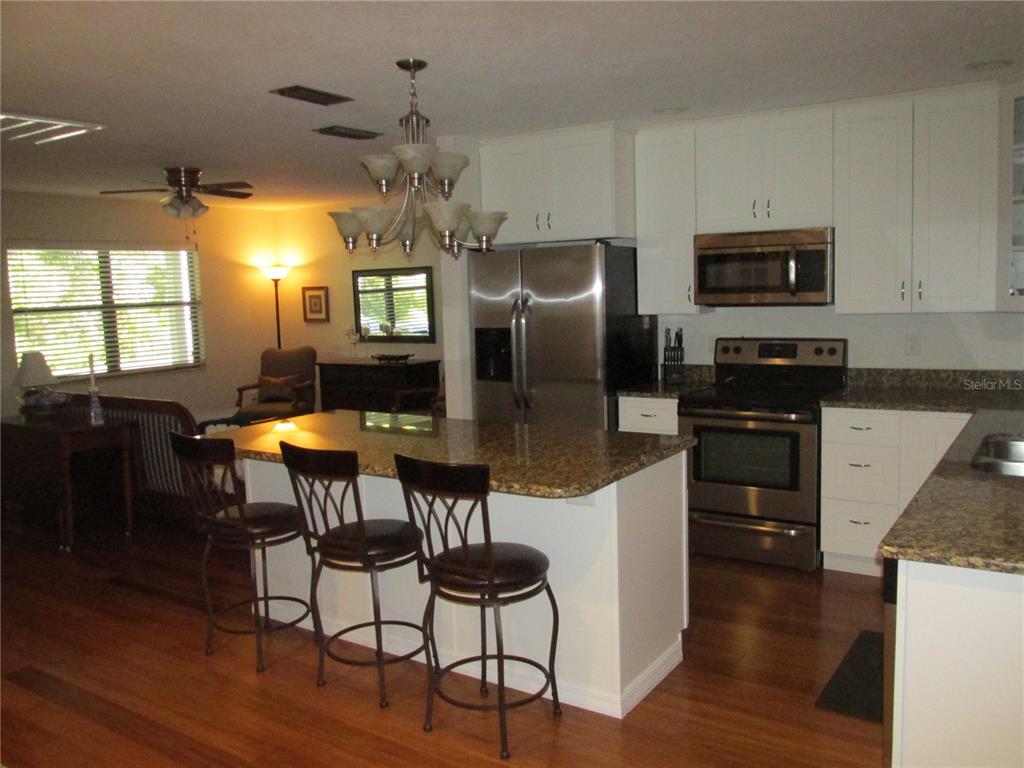 1767 Belvidere Road Englewood, FL 34223 - Photo 3 of 15 a kitchen with stainless steel appliances granite countertop a refrigerator a stove top oven a sink dishwasher and white cabinets with wooden floor