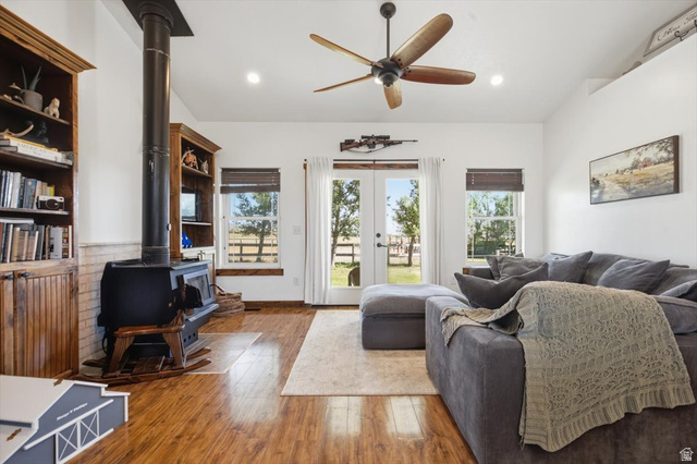 1634 West Arimo Road Arimo, ID 83214 - Photo 5 of 89 Living area featuring wood-finish flooring, a freestanding wood-burning stove, built-in wooden shelving, vaulted ceilings, and French doors opening to outdoor space