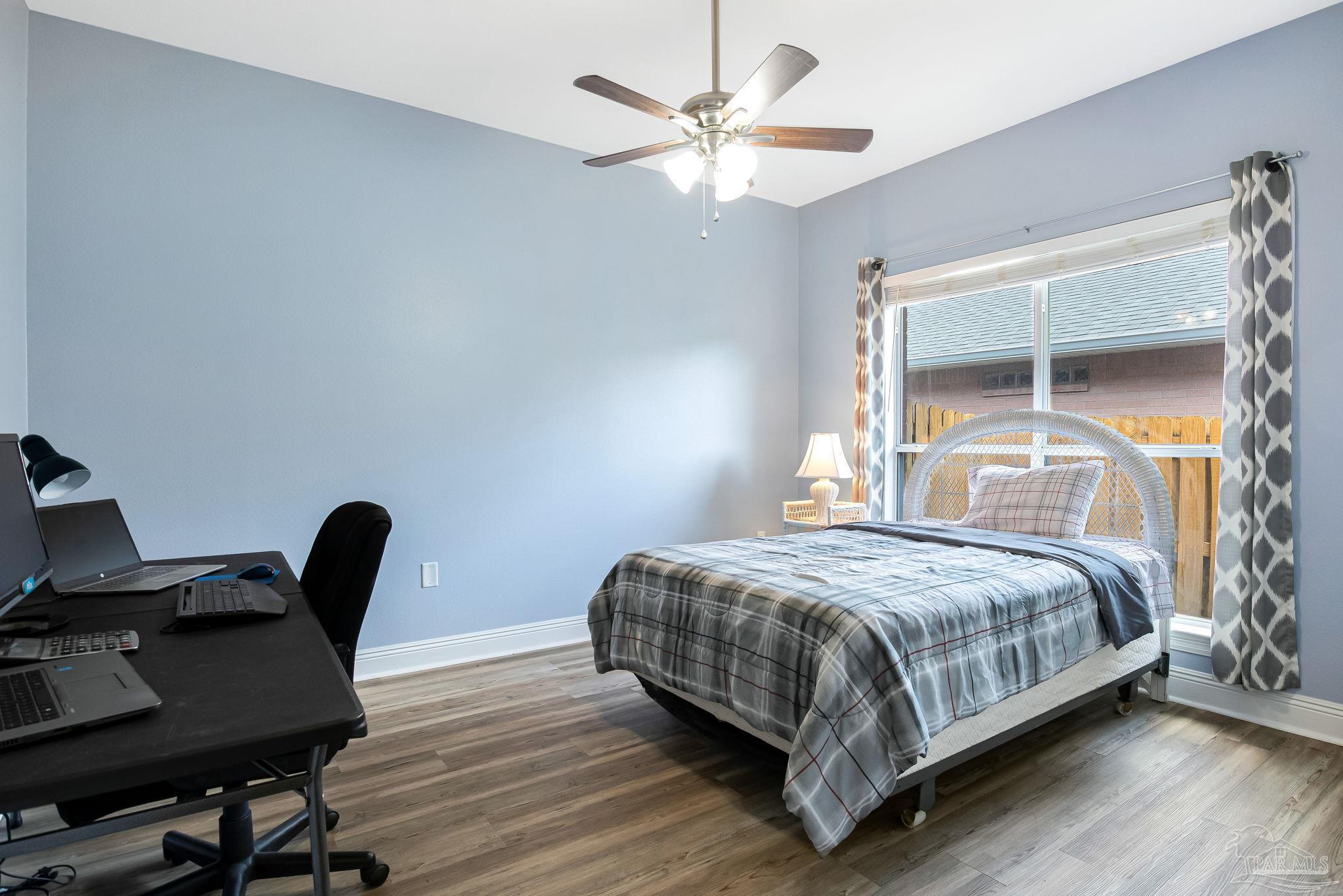 2822 Frederick Street Cantonment, FL 32533 - Photo 21 of 57 a bedroom with a bed a desk and chair with wooden floor
