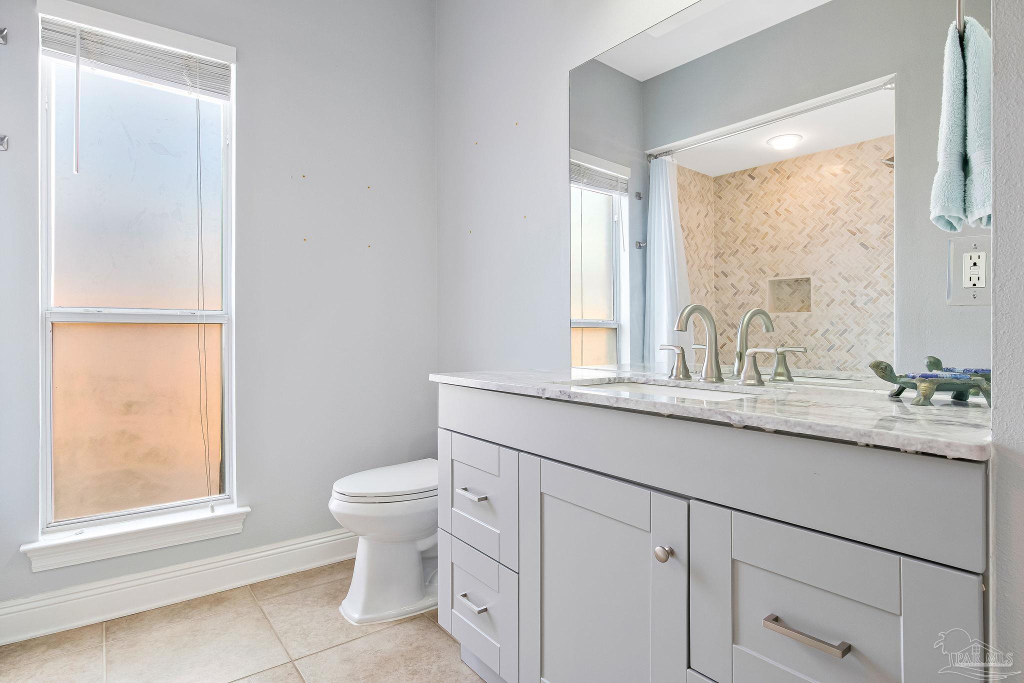 2822 Frederick Street Cantonment, FL 32533 - Photo 24 of 57 a bathroom with a granite countertop sink a toilet and a window