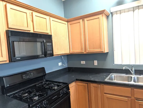 a kitchen with granite countertop a stove a sink and a microwave