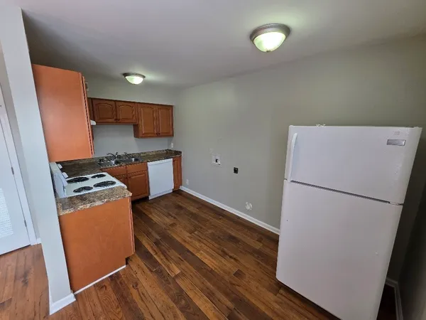 a kitchen with a refrigerator a stove and wooden floor