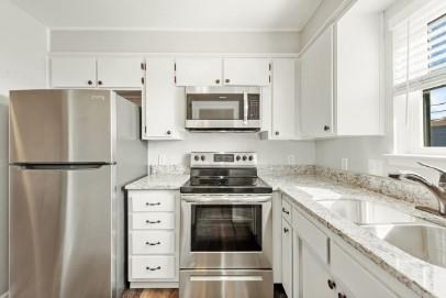 7700 Chapin Road, Unit 7 Fort Worth, TX 76116 - Photo 2 of 13 Modern kitchen featuring stainless steel appliances, white cabinetry, speckled countertops, a double basin sink, and wood-finish flooring