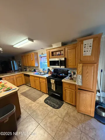 a kitchen with granite countertop a refrigerator and a stove top oven