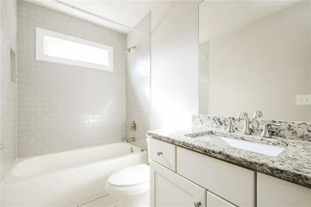 a bathroom with a granite countertop sink a toilet and bathtub