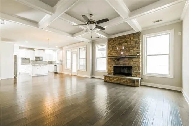 an empty room with wooden floor fireplace and windows