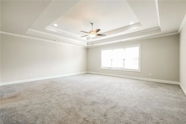 an empty room with a chandelier fan and windows