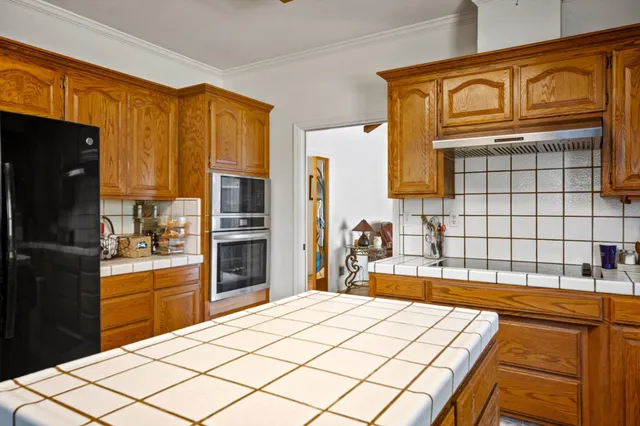 a kitchen with stainless steel appliances kitchen island granite countertop a refrigerator a stove top oven and a sink