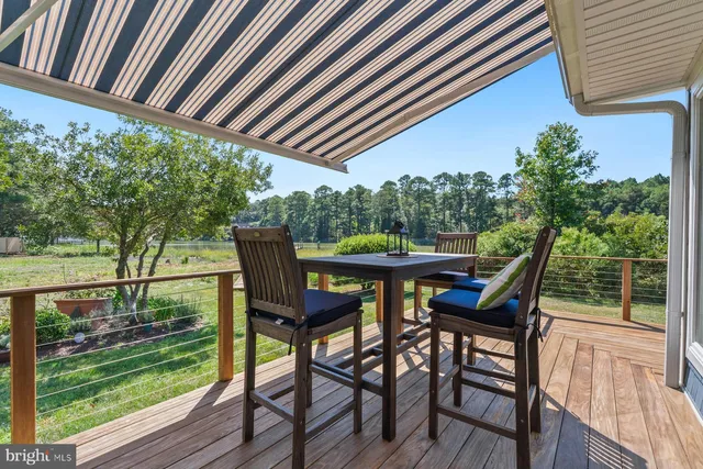 a view of trees and deck with wooden floor and fence next to a yard
