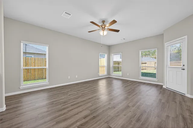 a view of an empty room with window and wooden floor