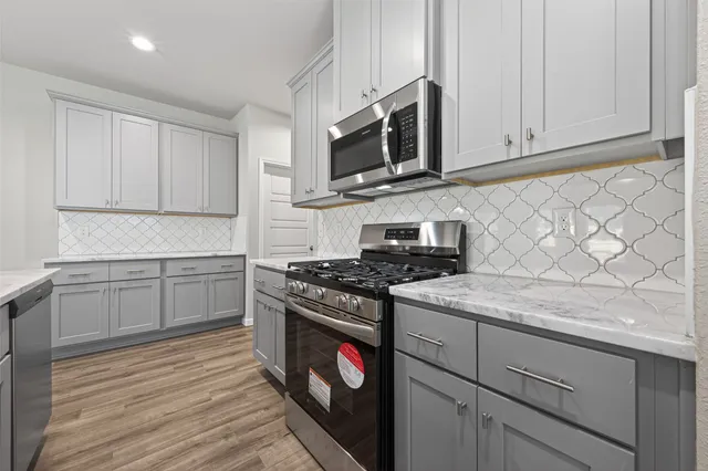 a kitchen with stainless steel appliances granite countertop a sink a stove top oven a counter space and cabinets