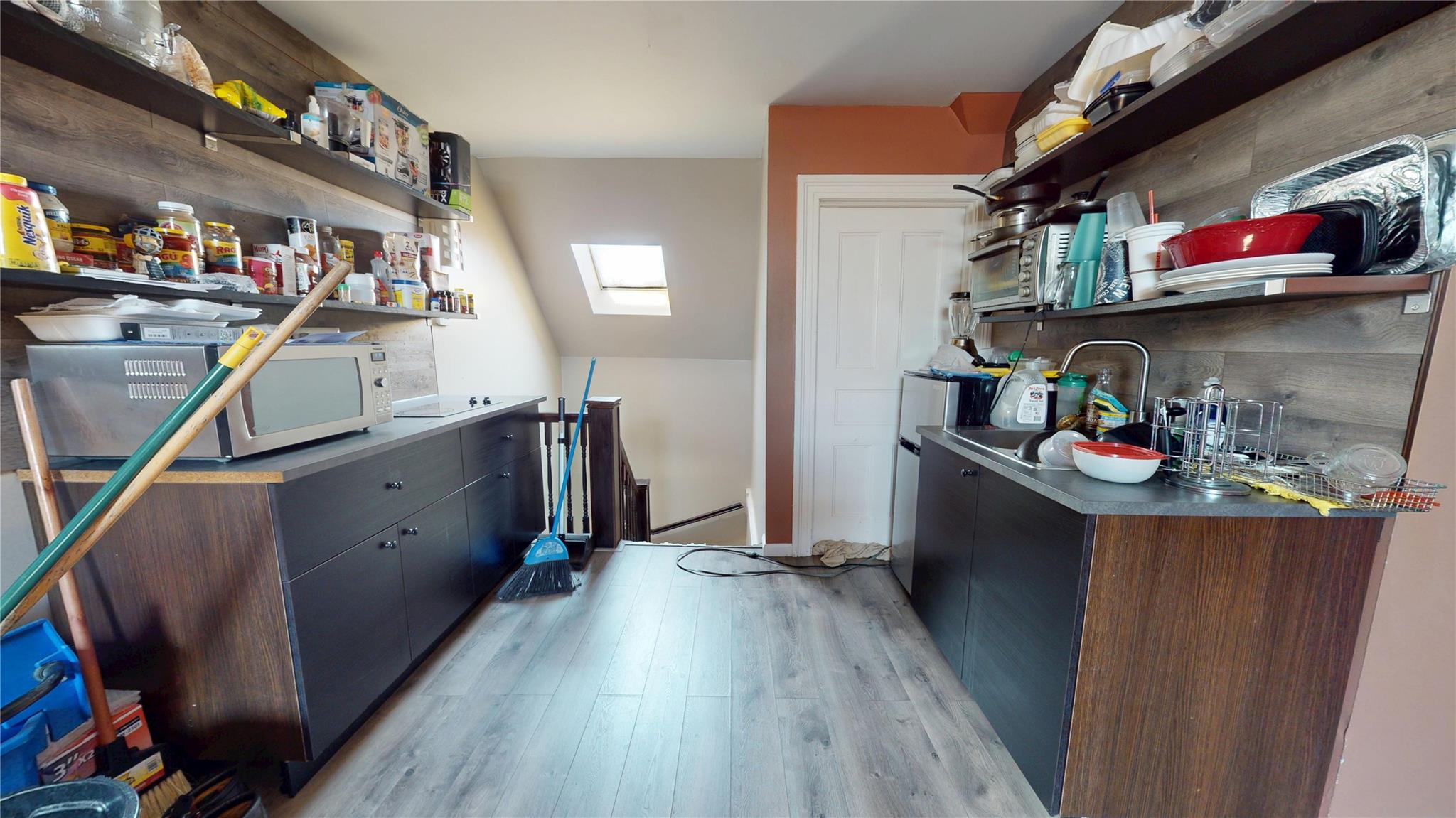 31-06 Healy Avenue Queens, NY 11691 - Photo 23 of 34 Kitchen featuring dark countertops, light wood-style floors, open shelves, and a skylight