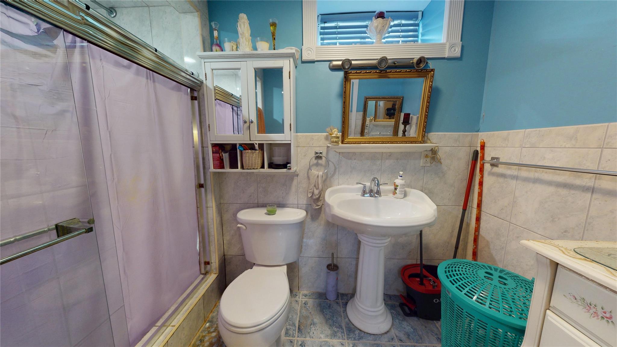 31-06 Healy Avenue Queens, NY 11691 - Photo 29 of 34 Full bath with tile walls, a shower with shower curtain, toilet, and a sink
