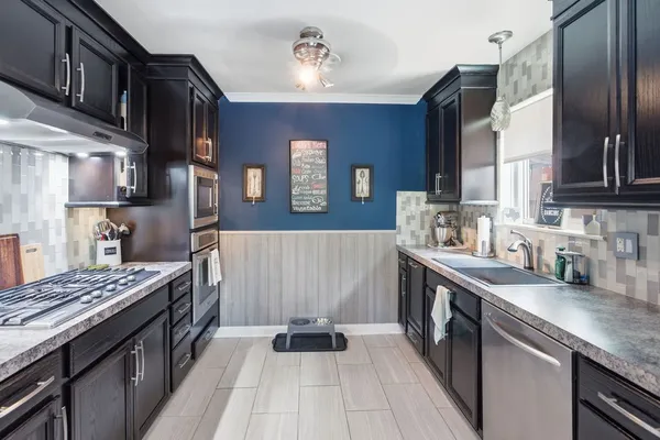 a kitchen with stainless steel appliances granite countertop a stove a sink dishwasher and cabinets with wooden floor