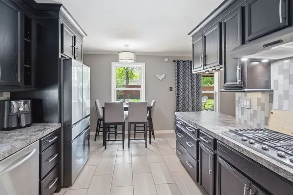 a kitchen with stainless steel appliances granite countertop a stove top oven a sink dishwasher a dining table and chairs