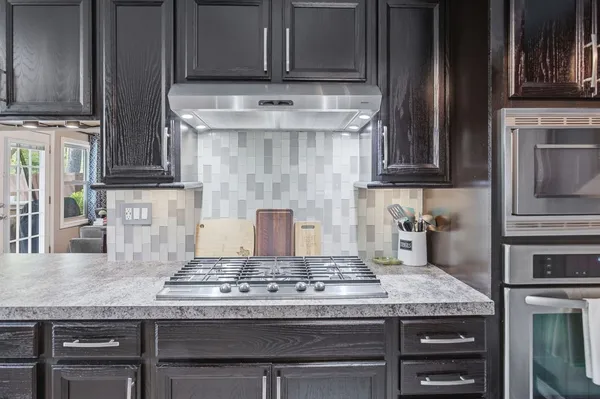 a kitchen with granite countertop a stove top oven cabinetry a sink and cabinets