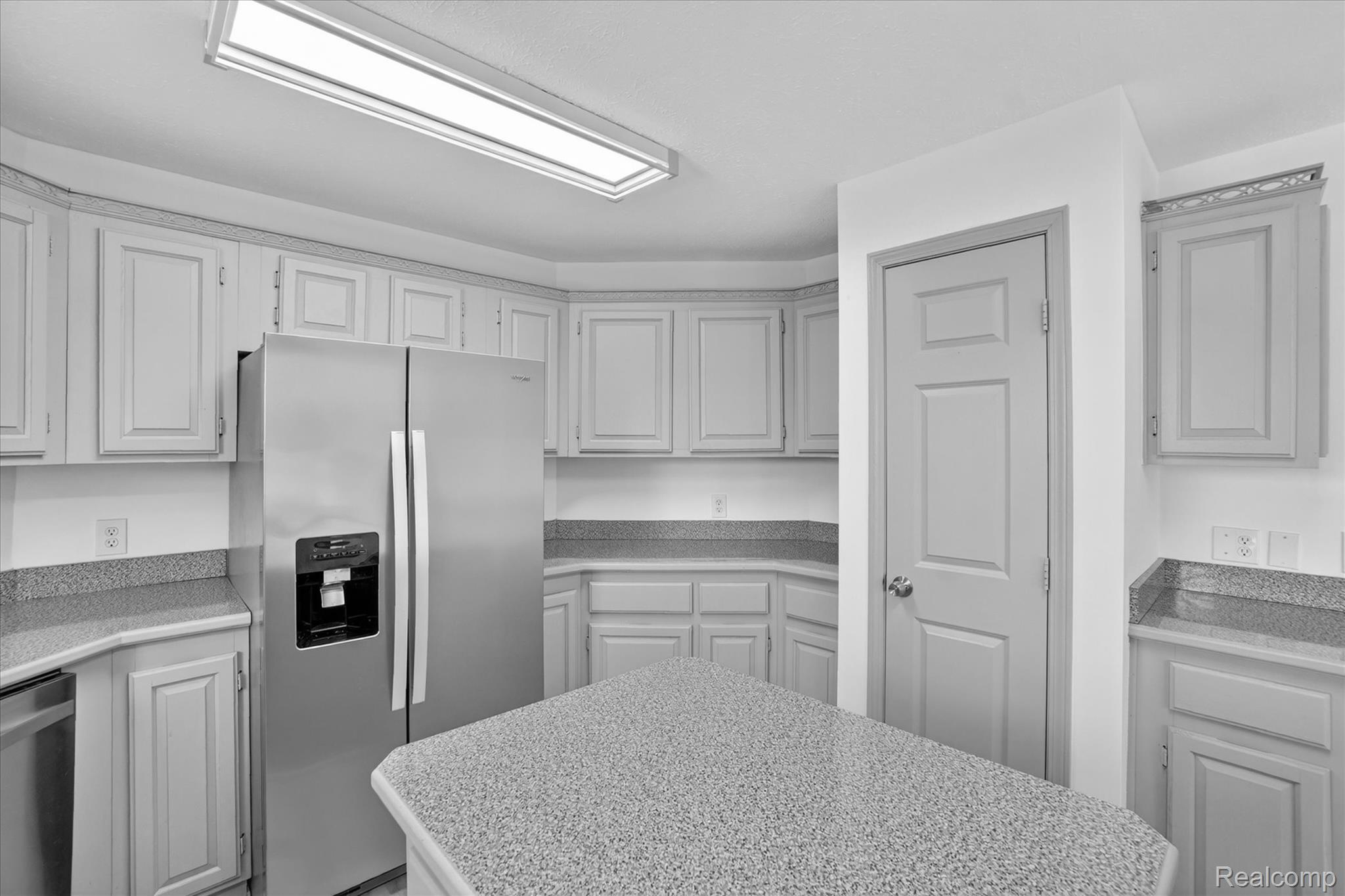 1400 North Every Road Mason, MI 48854 - Photo 13 of 33 Kitchen featuring an angled island with light speckled countertops, light-toned cabinetry, stainless steel refrigerator, and a recessed ceiling light fixture