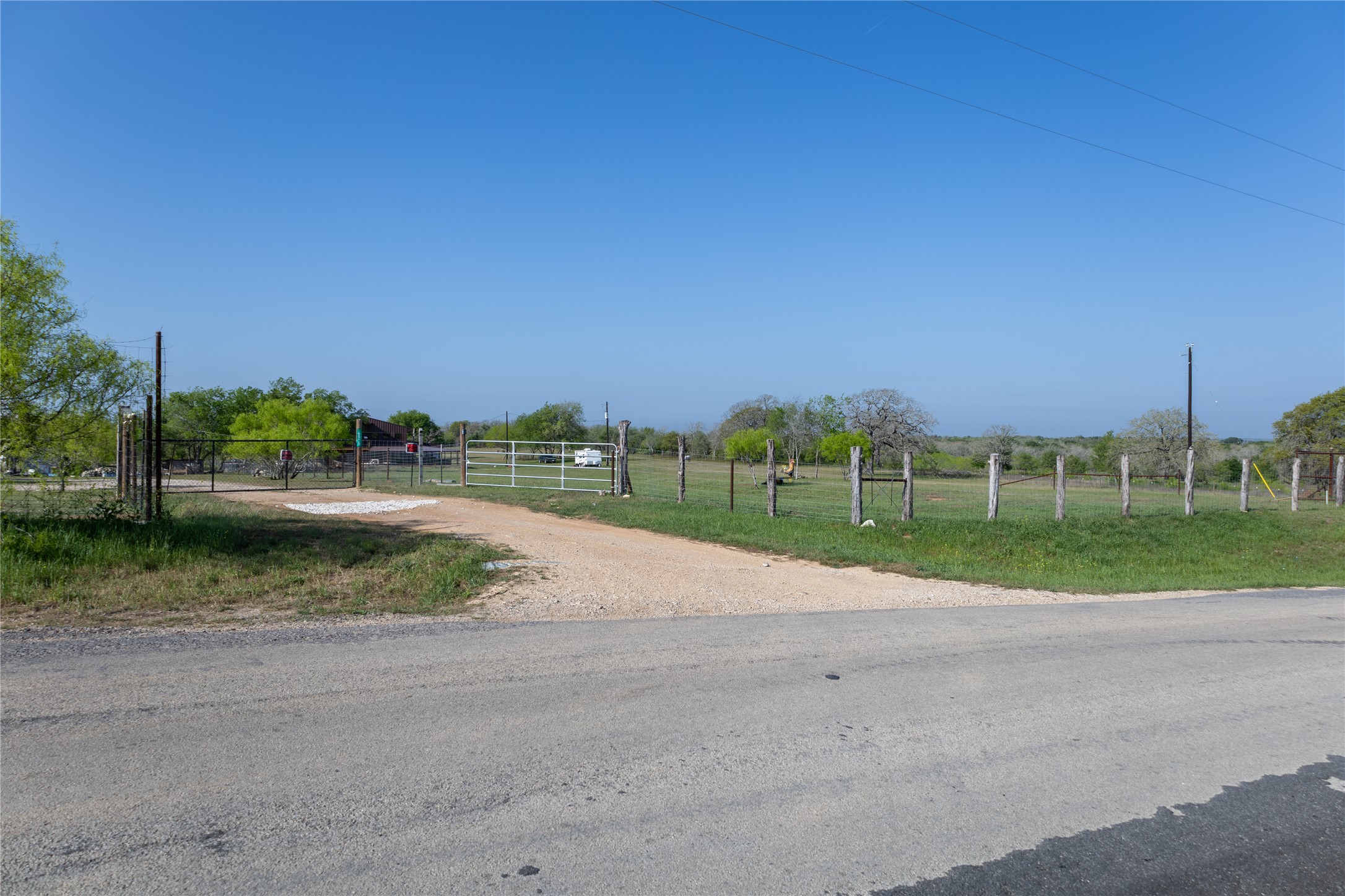 6575 Taylorsville Road Dale, TX 78616 - Photo 5 of 15 A long gravel driveway leads to an expansive, verdant lot, secured by a sturdy metal gate.
