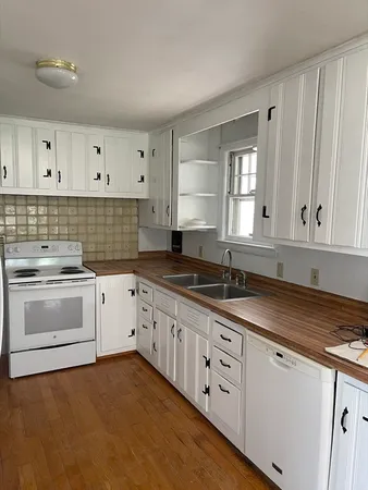 a kitchen with granite countertop white cabinets and white appliances
