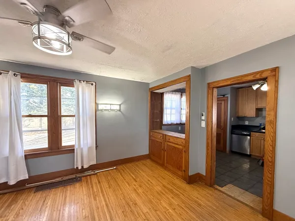 a view of a room with wooden floor a ceiling fan and windows
