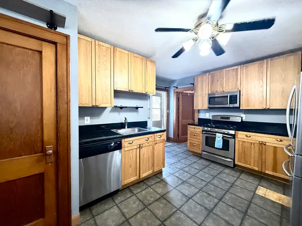 a large kitchen with stainless steel appliances granite countertop a stove a sink and a microwave
