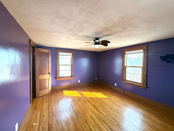 a view of an empty room with window and wooden floor