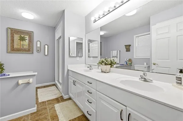 a spacious bathroom with a double vanity sink a mirror and a