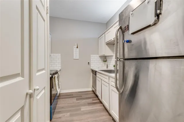a kitchen with a refrigerator a sink and white cabinets