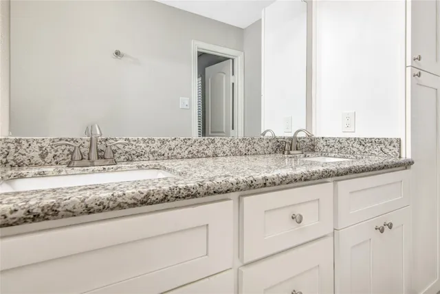a bathroom with a granite countertop sink and white cabinets