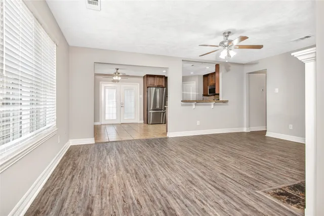 a view of empty room with wooden floor and fan