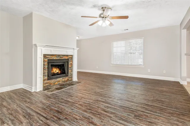 an empty room with windows fireplace and wooden floor