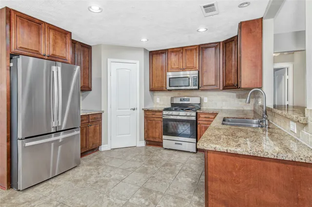 a kitchen with granite countertop a refrigerator stove and sink