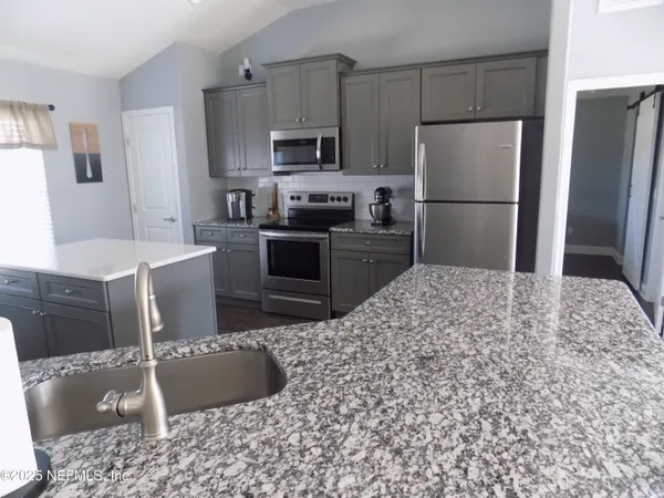 a kitchen with stainless steel appliances kitchen island granite countertop a refrigerator and a stove top oven