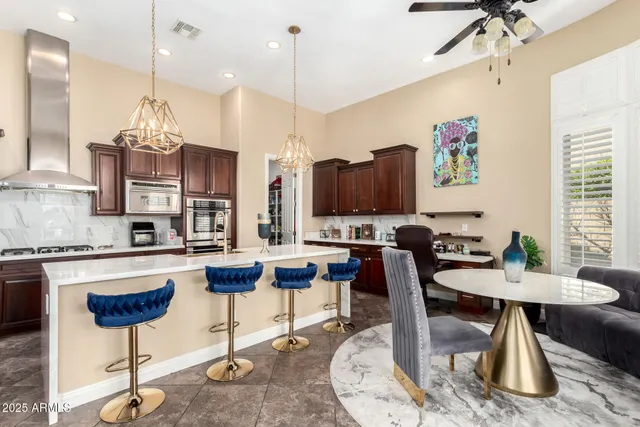 a kitchen with stainless steel appliances granite countertop a stove top oven a refrigerator a sink and chairs