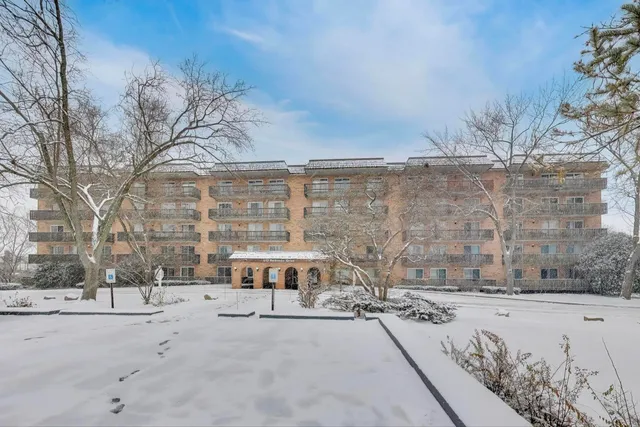 a building with a bench and trees covered with snow in the background