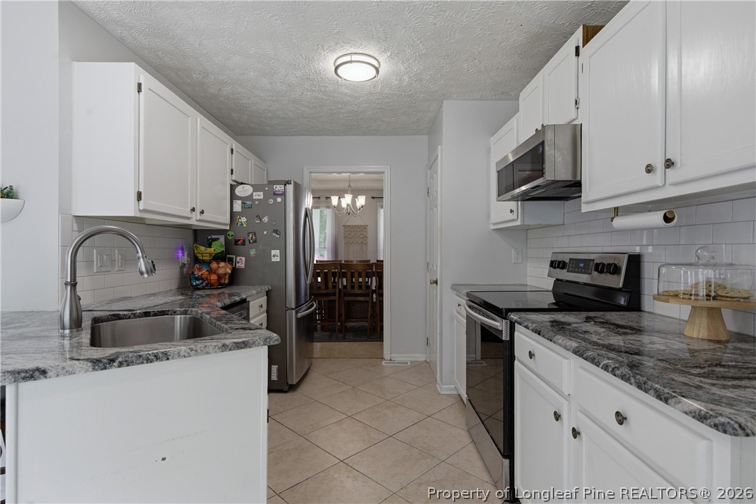 1837 Nuthatch Road Fayetteville, NC 28304 - Photo 20 of 43 a kitchen with granite countertop a sink a stove and refrigerator