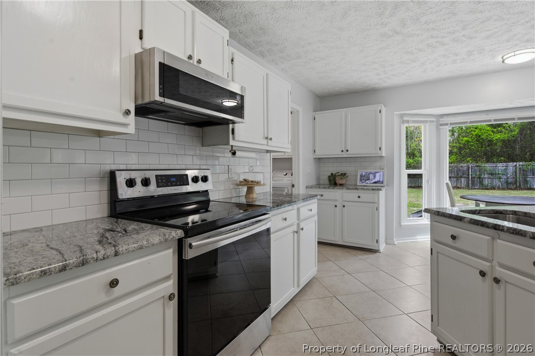 1837 Nuthatch Road Fayetteville, NC 28304 - Photo 23 of 43 a kitchen with stainless steel appliances granite countertop grey cabinets a stove a sink and a microwave