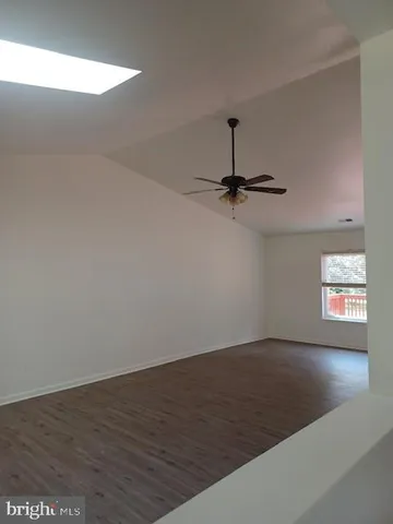 an empty room with wooden floor chandelier fan and windows