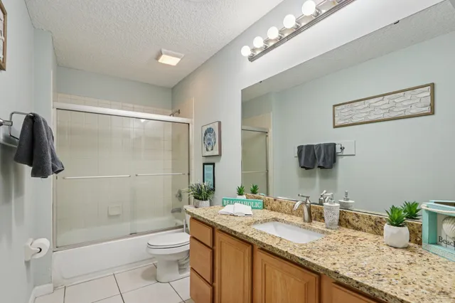 a bathroom with a granite countertop sink a toilet a mirror and shower