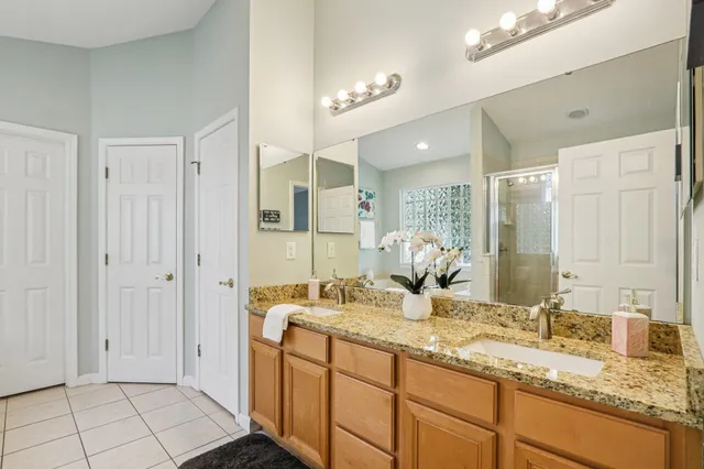 a bathroom with a granite countertop double vanity sink a mirror and a