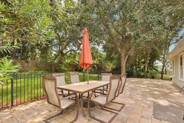 a view of a patio with a table and chairs a barbeque with wooden fence and floor