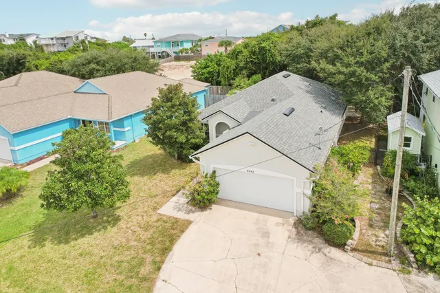 an aerial view of a house with a yard and trees all around